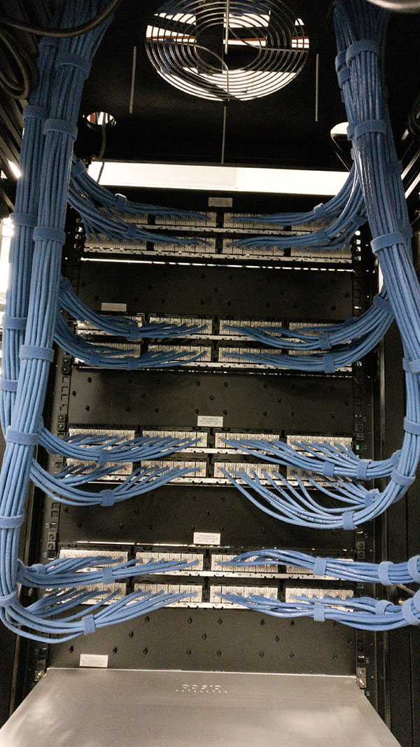 A bunch of wires hanging from the side of a rack.