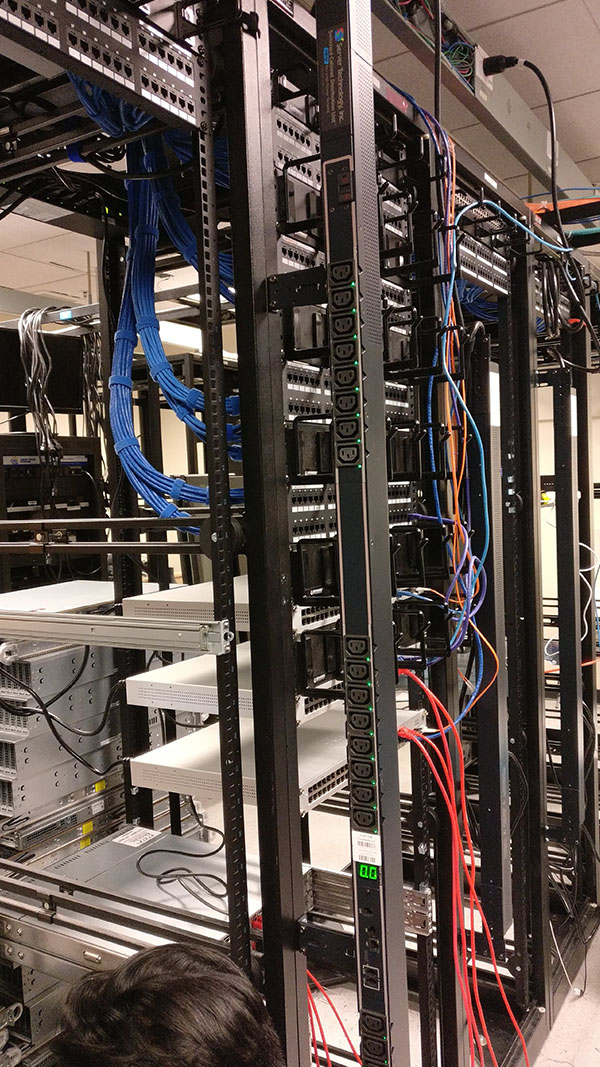 A bunch of wires hanging from the side of a rack.