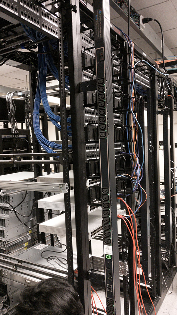 A bunch of wires hanging from the side of a rack.