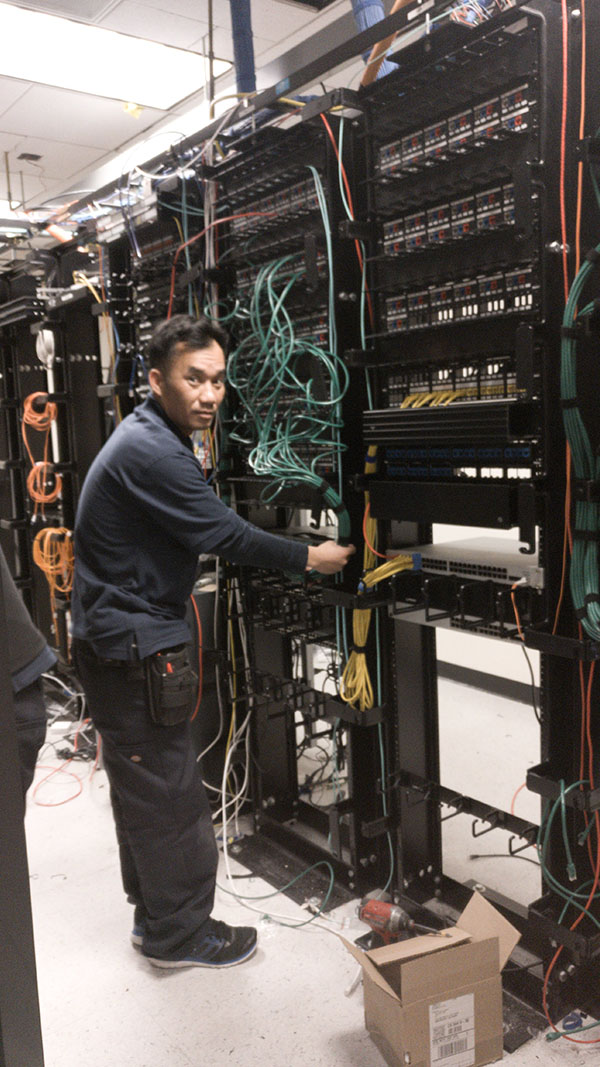 A man working on some wires in an electrical room.