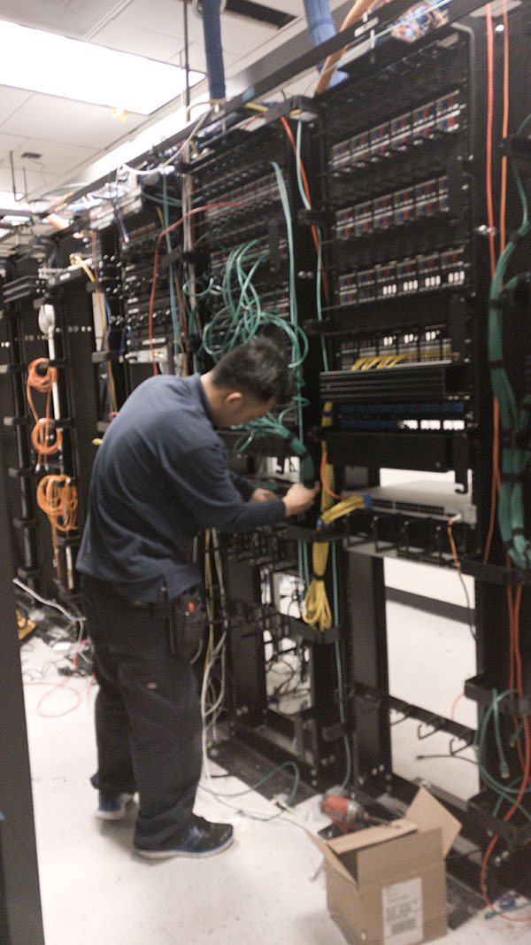 A man working on wires in an electrical room.