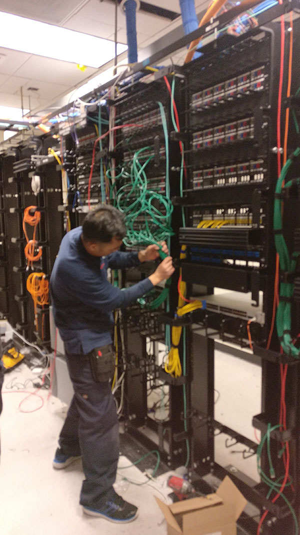 A man working on wires in an electrical room.