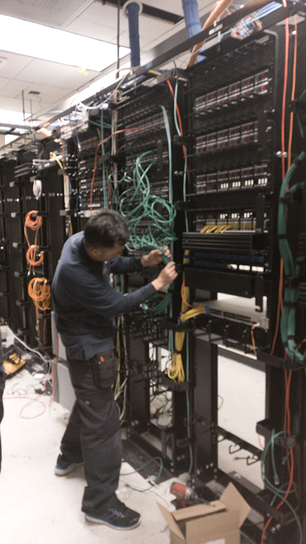 A man working on wires in an electrical room.