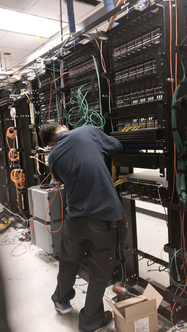 A man working on some wires in an electrical room.