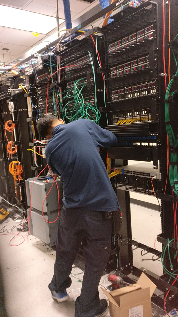 A man working on wires in an electrical room.