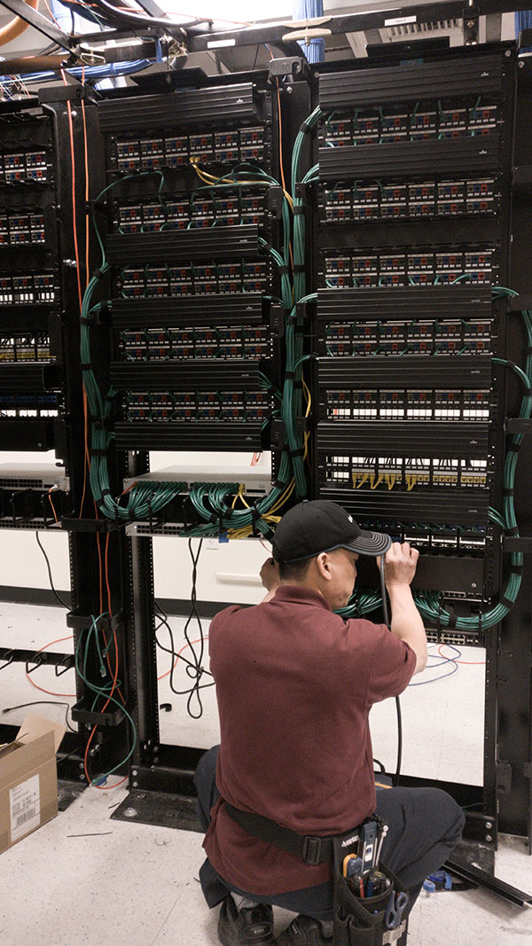 A man working on some wires in an electrical room.
