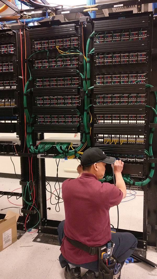 A man working on some wires in an electrical room.