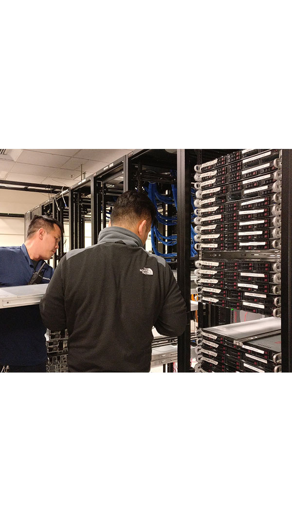 Two men working in a server room with racks of servers.