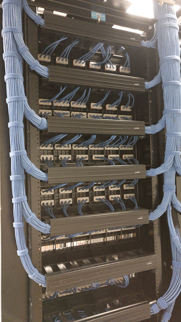 A bunch of wires hanging from the side of a rack.