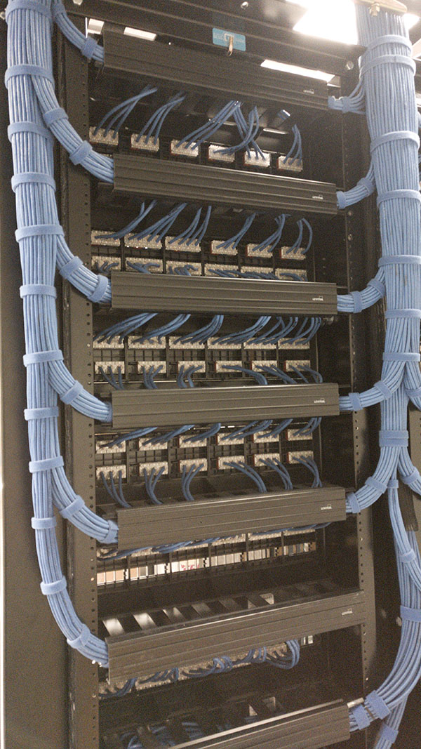A bunch of wires hanging from the side of a rack.