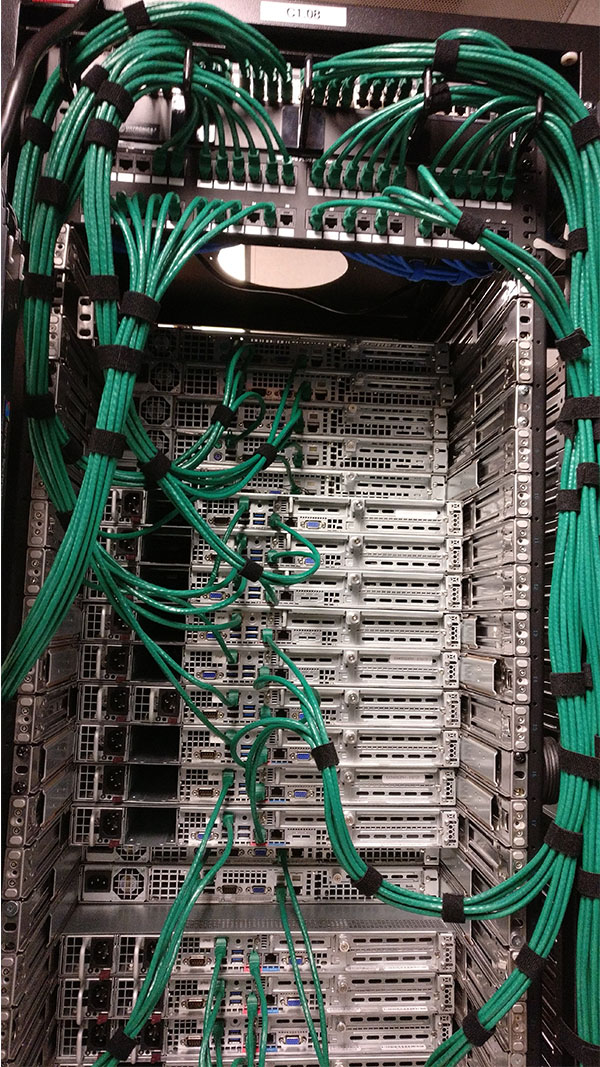 A rack of servers with green wires hanging from the top.