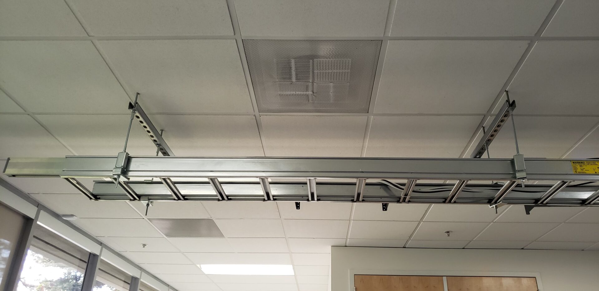 A ceiling with many pipes and wires hanging from it