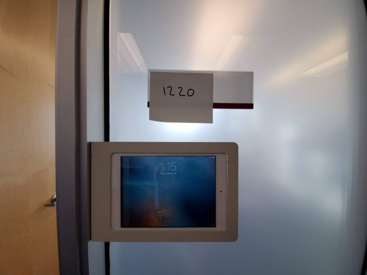 A tablet computer mounted to the side of a glass door.