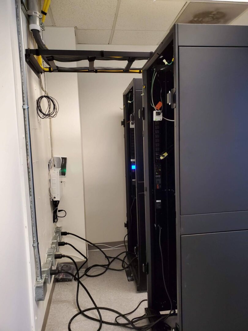A room with many wires and some black cabinets